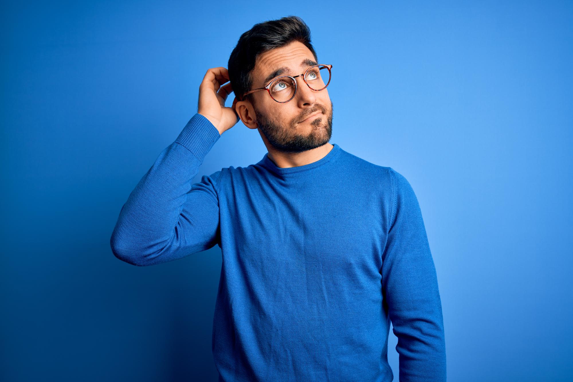 young-handsome-man-with-beard-wearing-casual-sweater-glasses-blue-background-confuse-wondering-about-question-uncertain-with-doubt-thinking-with-hand-head-pensive-concept
